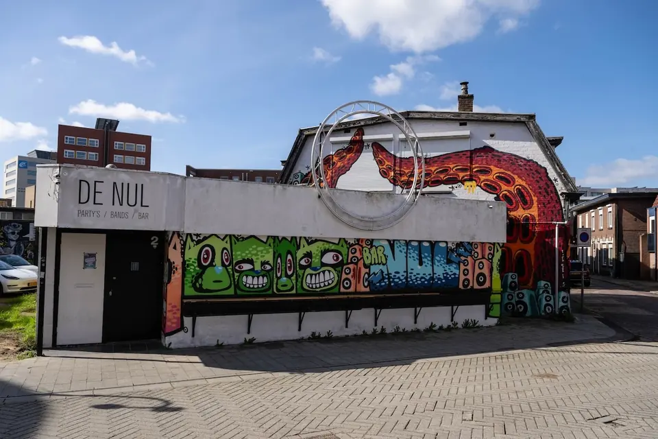 De gevel van bar De Nul in Hengelo met graffiti en een blauwe lucht