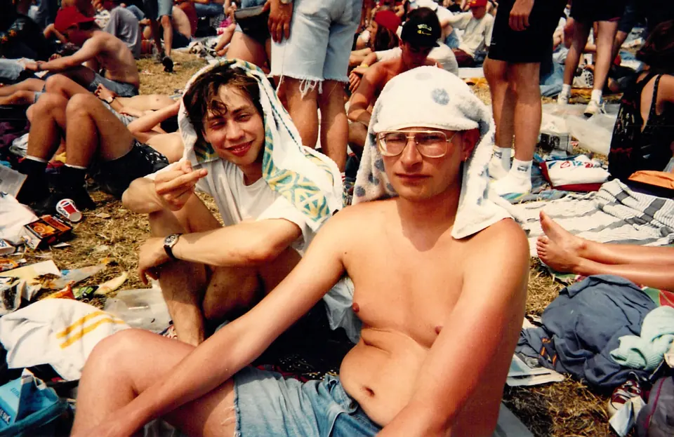 Twee festivalgangers met handdoeken om het hoofd zitten in het publiek op het grasveld
