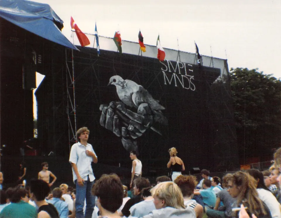 Het podium van Simple Minds met een duif op het backdrop en publiek op de voorgrond