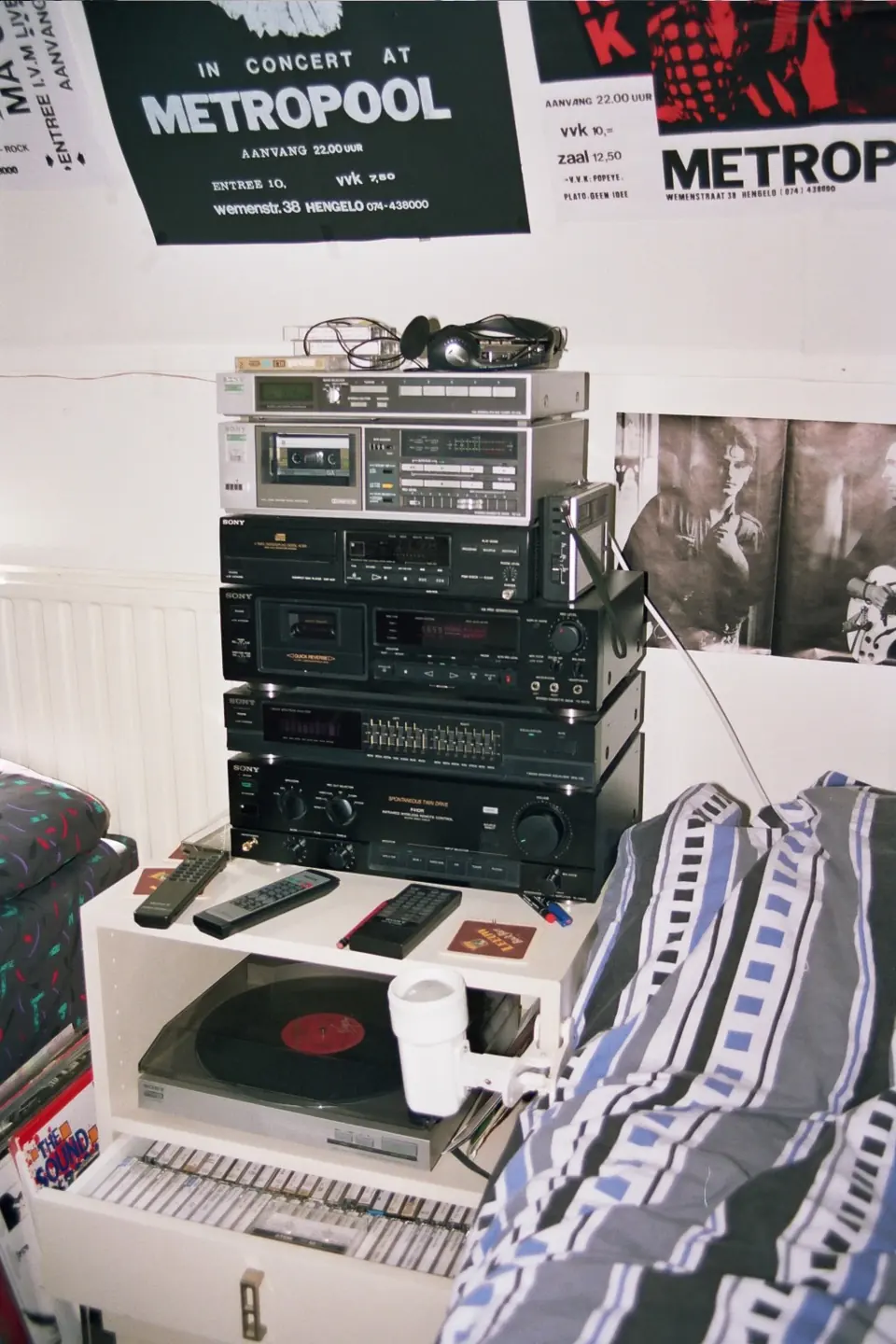Een Sony-stereotoren met draaitafel in een studentenkamer, met een Metropool-poster aan de muur